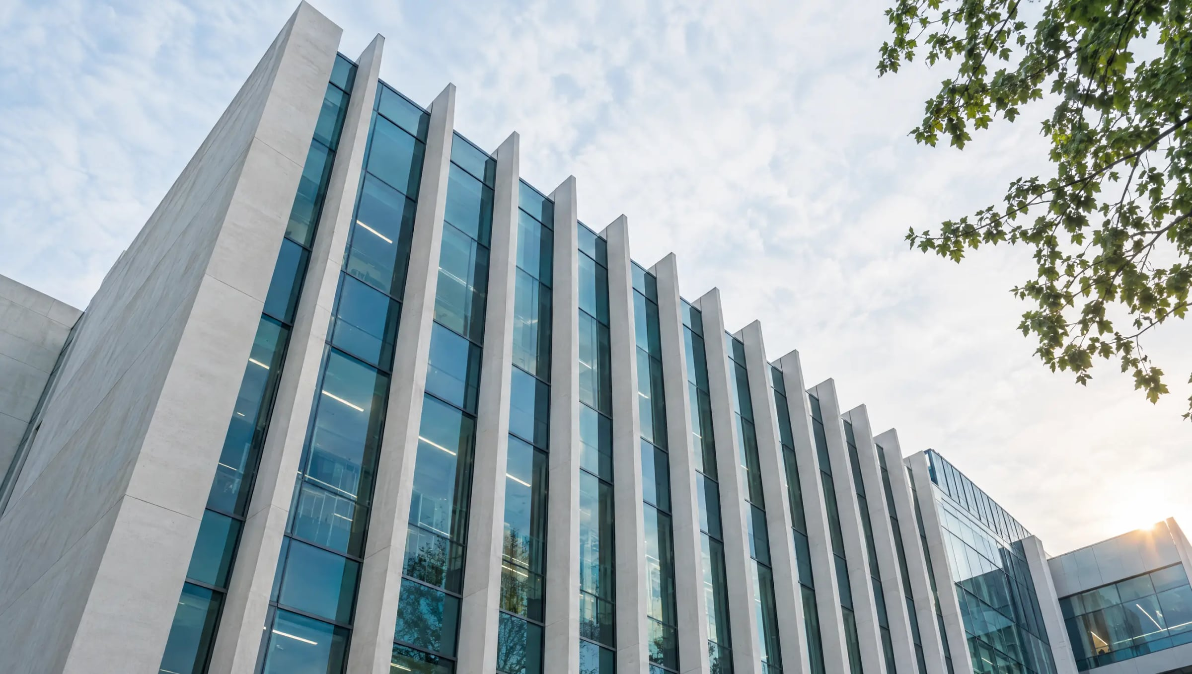 Looking up at a research building of white concrete fins and tall glass