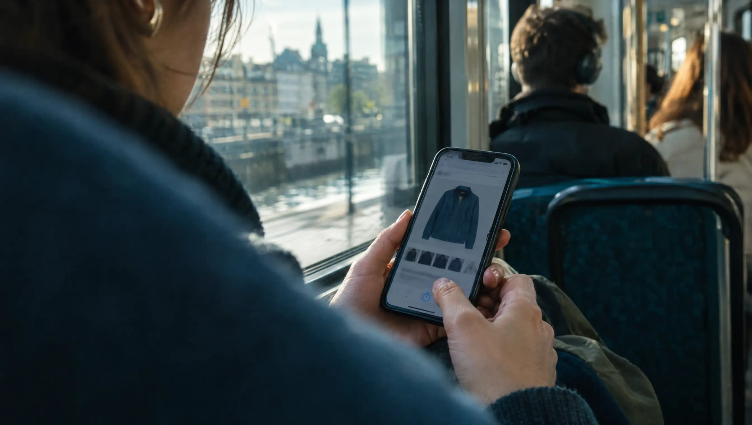 A shopper on a tram saving a jacket from a shopping app on a phone