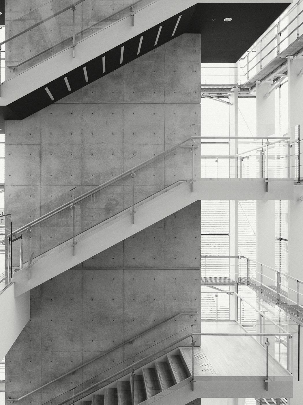 A concrete stair tower seen through a glass facade