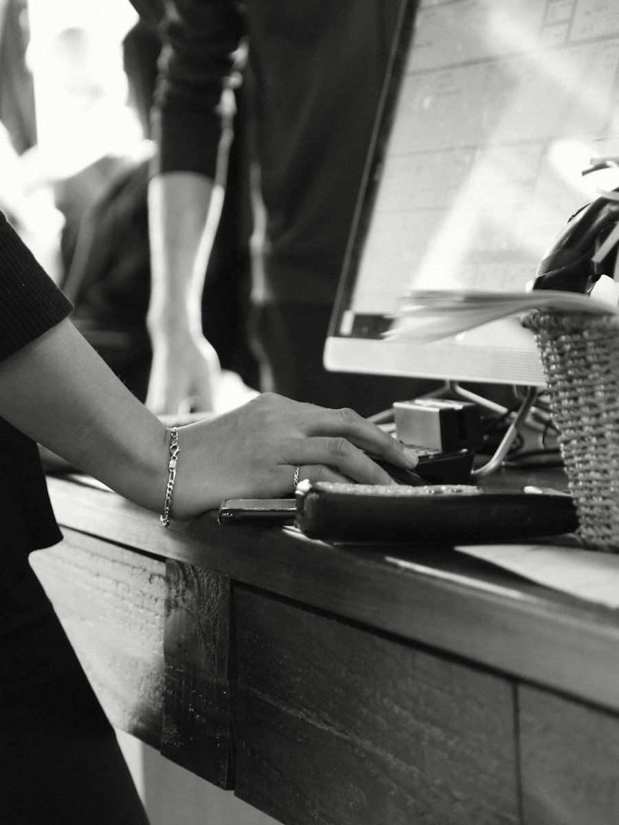 A hand at a shop counter beside a card terminal