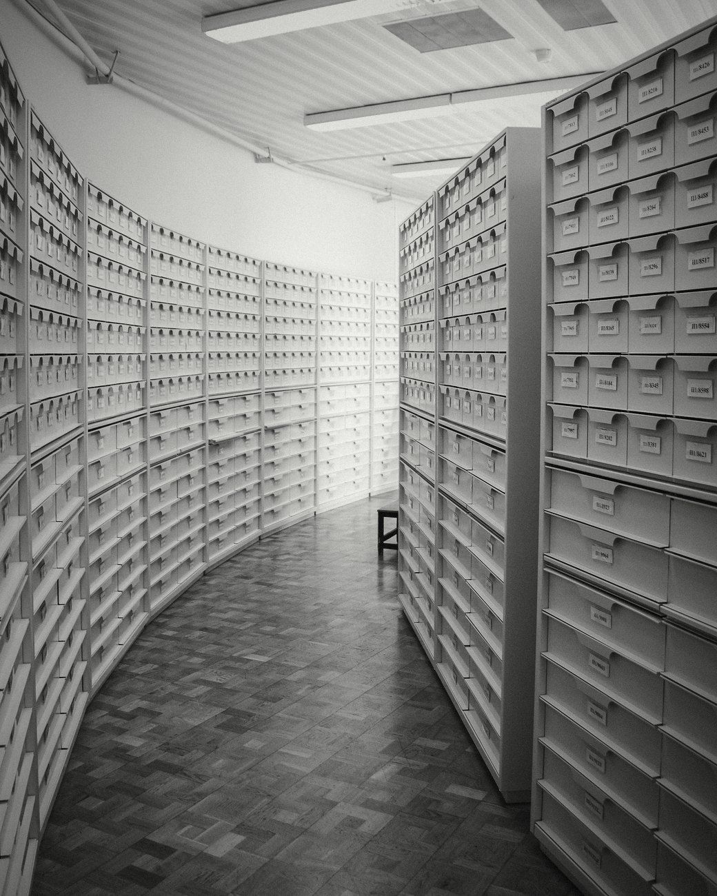 A curved archive corridor lined with white drawers