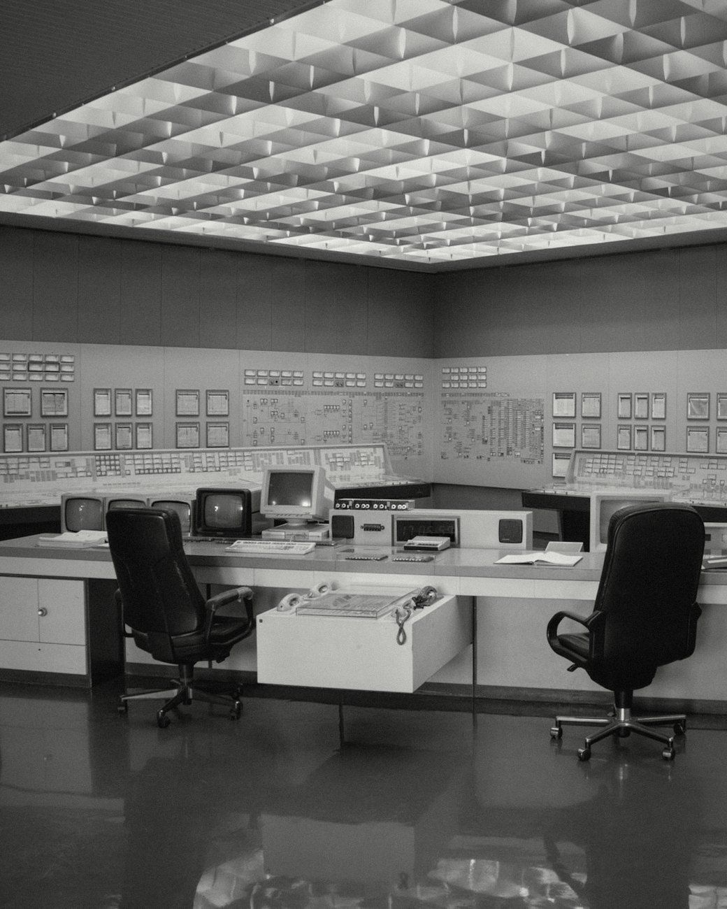 An empty control room with desks, screens and wall panels