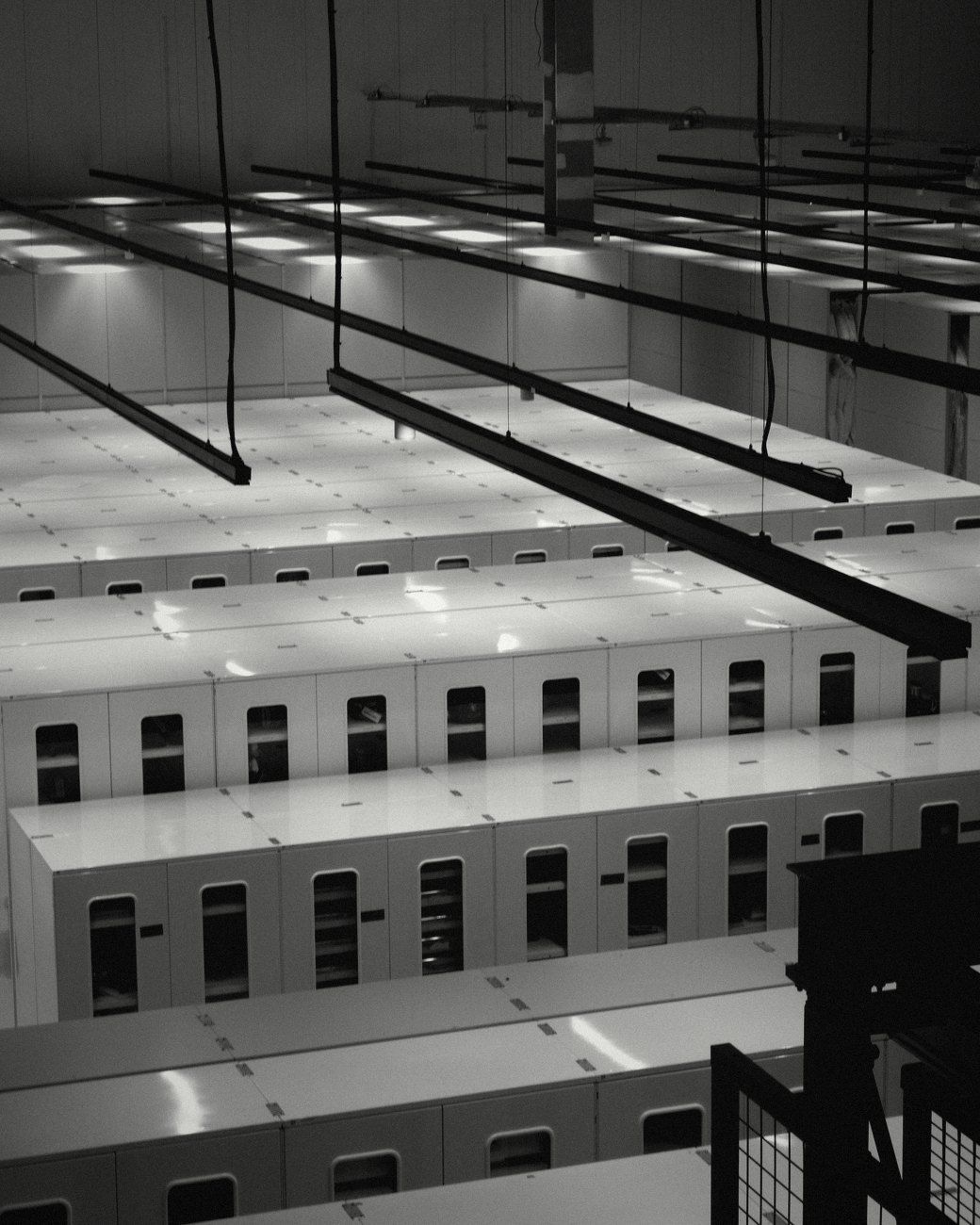 Rows of white server cabinets under hanging light rails