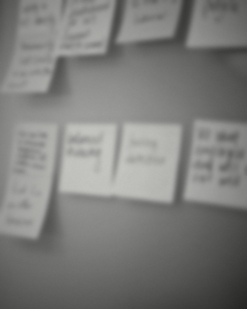 Two rows of handwritten sticky notes on a glass wall, out of focus